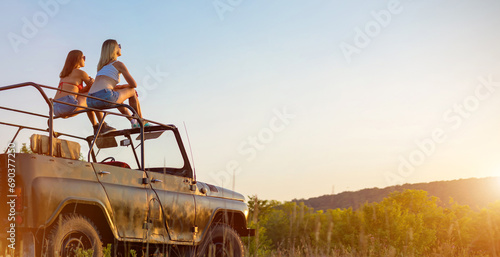 Couple of girls travelling on the vintage cabriolet. Rural background. photo