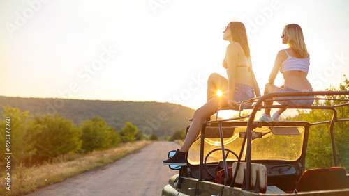 Couple of girls travelling on the vintage cabriolet. Rural background.