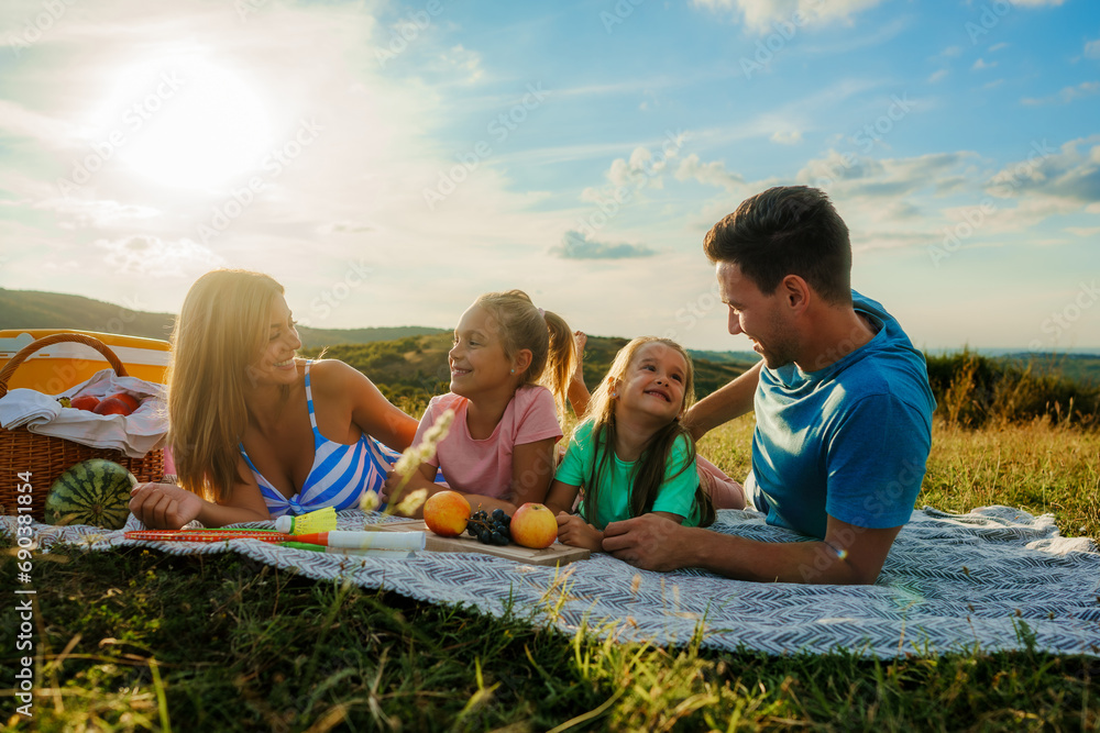 Obraz premium The family is lying on a blanket surrounded by fruit, having a picnic for the last day of summer vacation