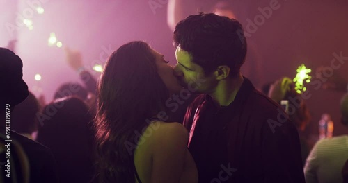 Couple, kiss and lights in a nightclub for dancing, fun and a night out at a new years event. Crowd, people or man and a woman at a disco, club or party with entertainment and love with music photo