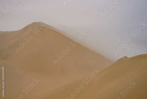 Large sand dunes in Namib Desert on cloudy, hazy day 