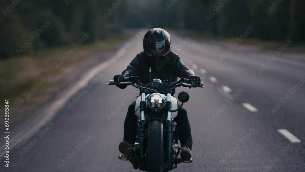 Young man in black leather jacket rides stylish motorcycle on highway outside city. Slow motion Young man in black leather jacket rides stylish motorcycle on highway outside city. Slow motion