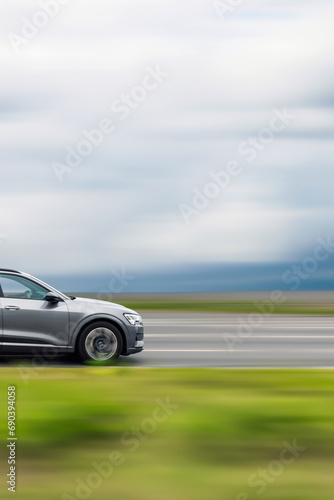 Car driving on the road. Gray car in motion, speed blurred background, side view of the front of the car