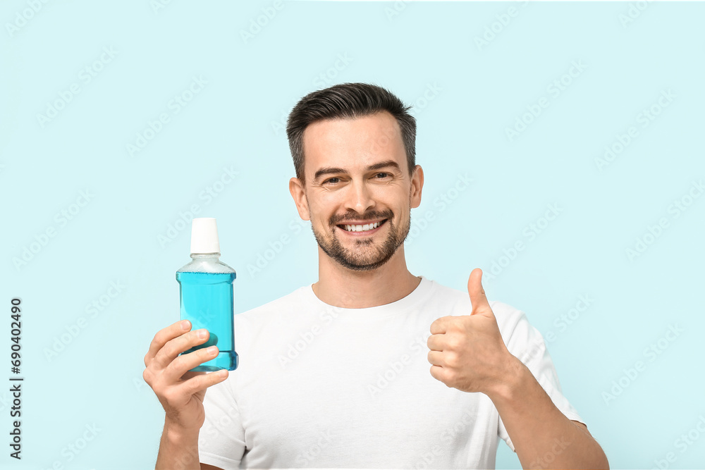 Handsome man with mouth rinse showing thumb-up on blue background Handsome man with mouth rinse showing thumb-up on blue background