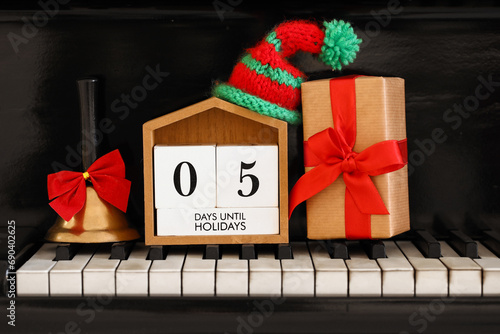 Calendar with text 5 DAYS UNTIL HOLIDAYS, Christmas gift and decor on piano keys photo