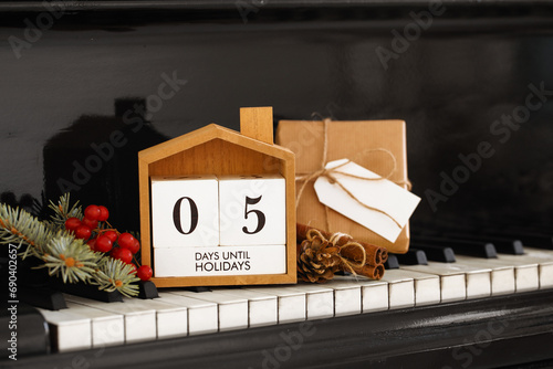 Calendar with text 5 DAYS UNTIL HOLIDAYS, gift box and Christmas decorations on piano keys