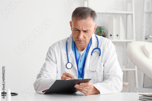 Mature doctor video chatting at table in office
