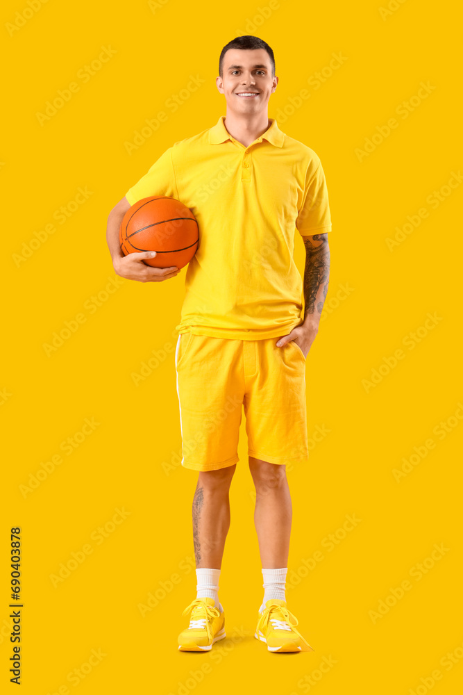 Young basketball player on yellow background