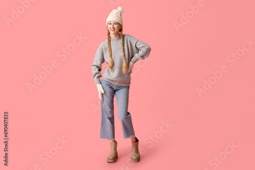 Beautiful young happy woman in warm winter clothes on pink background