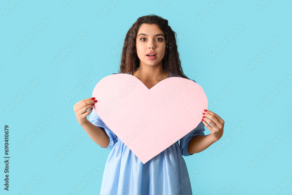 Beautiful young woman with pink paper heart on blue background Beautiful young woman with pink paper heart on blue background