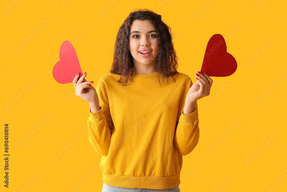 Beautiful young woman with red paper hearts on yellow background Beautiful young woman with red paper hearts on yellow background
