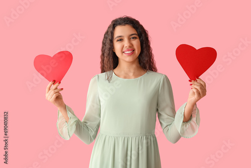Happy young woman with red paper hearts on pink background