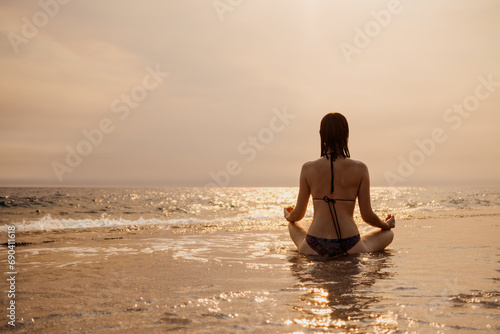 A serene backdrop of a setting sun as a woman meditates on the beach, finding inner peace