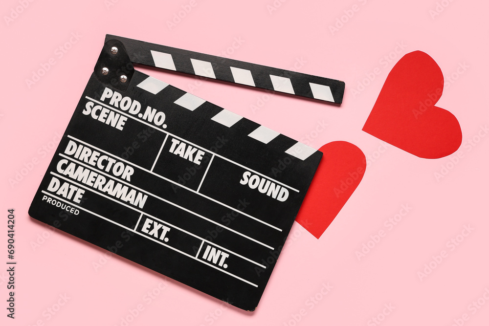 Movie clapper and paper hearts on pink background. Valentine's Day celebration