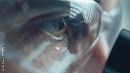 Extreme close-up view of scientist in protective glasses looking into microscope in laboratory photo