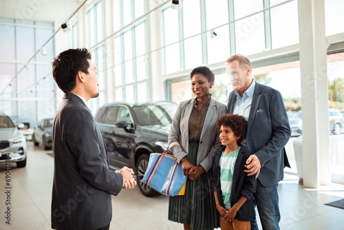 Family at car dealership talking to salesman photo
