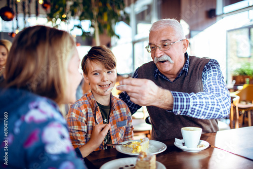 Happy grandfather eating dessert with grandchildren in cafe photo
