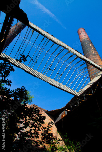 Reclaimed by Nature: Rustic Industrial Remains Under Clear Blue Sky photo