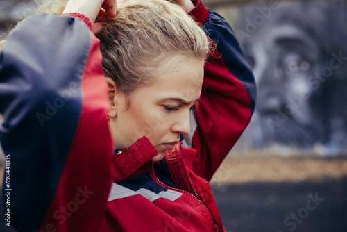 Portrait of a young female runner straightens hair outdoor stadium photo