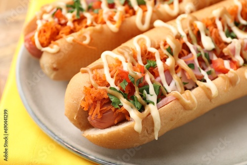 Delicious hot dogs with bacon, carrot and parsley on table, closeup