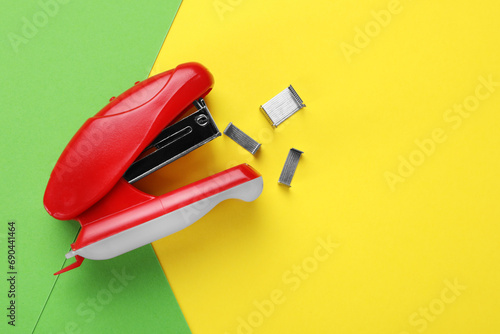 Red stapler with staples on color background, flat lay. Space for text