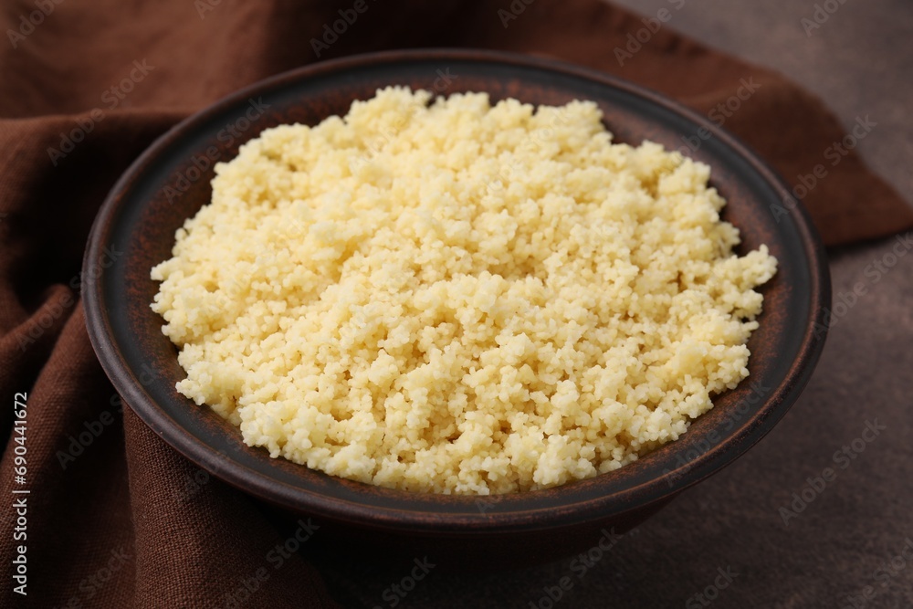 Tasty couscous in bowl on brown table, closeup Tasty couscous in bowl on brown table, closeup