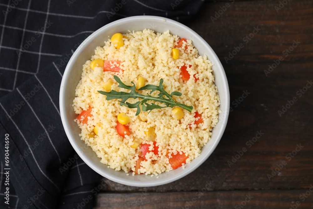 Tasty couscous with pepper, corn and arugula in bowl on wooden table, top view Tasty couscous with pepper, corn and arugula in bowl on wooden table, top view