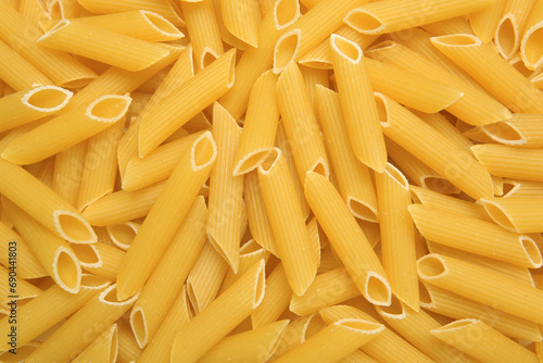Uncooked penne pasta as background, top view