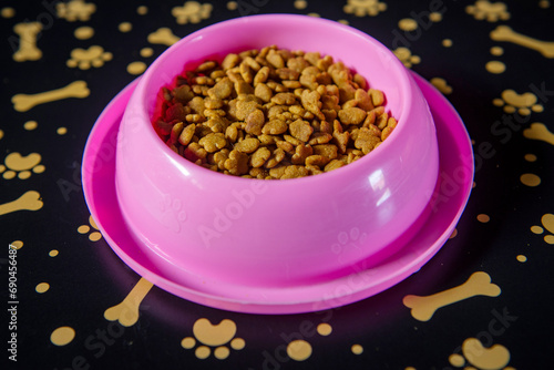 Różowa miska z suchą karmą dla kota na macie do karmienia zwierząt domowych © Anna