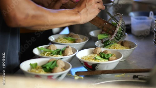 Preparing chicken noodles. View of a penjual mie ayam bakso or meatball chicken noodle seller who is making chicken noodles for the buyer. Selective focus photo