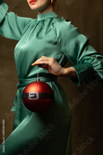 A woman in a green dress holding a Christmas ornament
