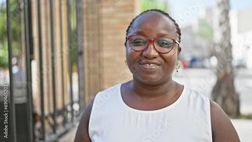 Confident african american woman standing on urban street, radiating joy and positivity, her contagious laughter spreading happiness. her braids bouncing, glasses glinting, truly loving life.