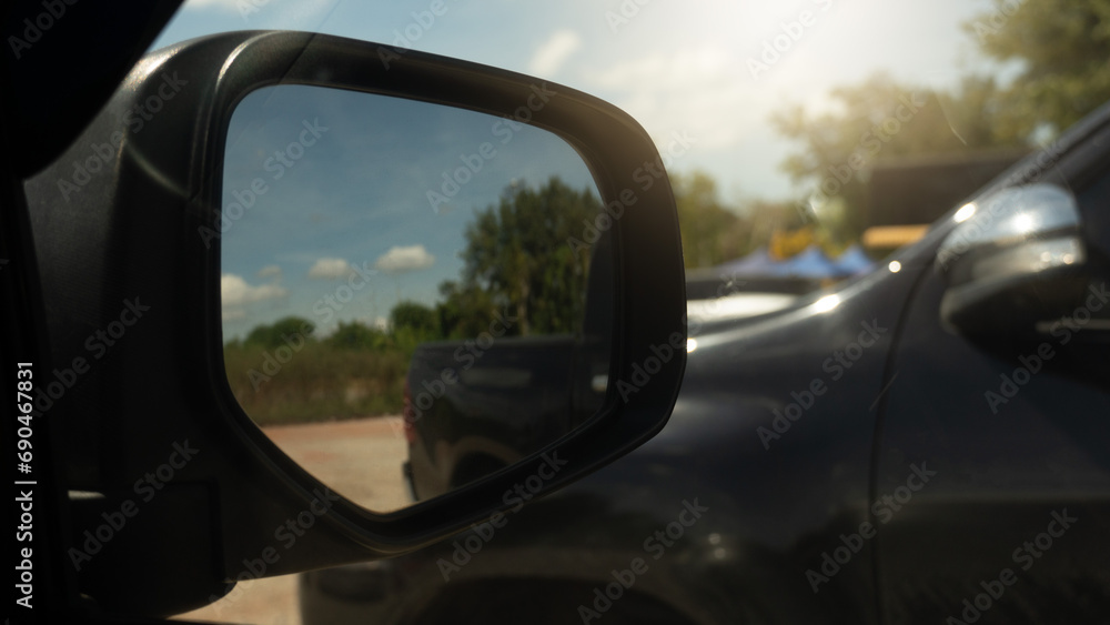 Mirror wing of car with other car parking beside. In ther mirror wing with soil road in the glass.