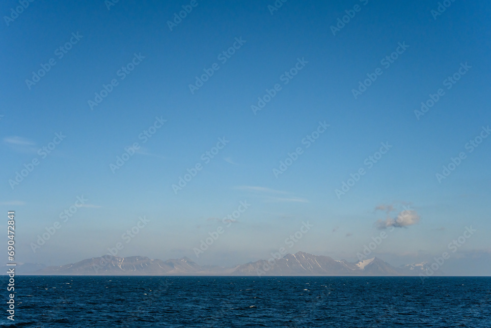 Calm and peaceful nature background, arctic ocean with a mountain range on the horizon and early morning light blue sky
Calm and peaceful nature background, arctic ocean with a mountain range on the horizon and early morning light blue sky