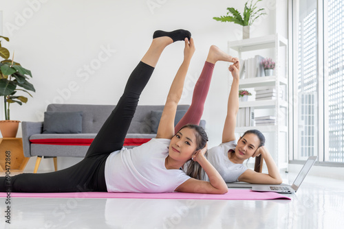 Two Women Doing Yoga While Watching a Video on a Laptop