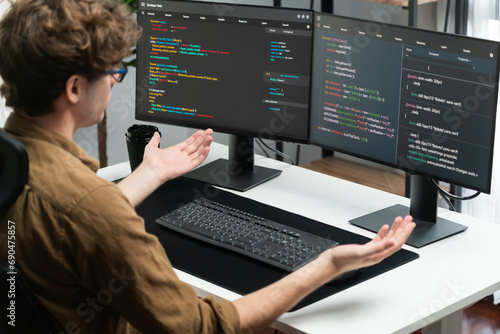 Obraz na płótnie IT developer working online software development on pc monitors at modern home office on coding application screens, creating updated latest program firmware information version concept. Gusher.