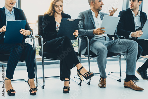 Businesswomen and businessmen holding resume CV folder while waiting on chairs in office for job interview. Corporate business and human resources concept. uds photo