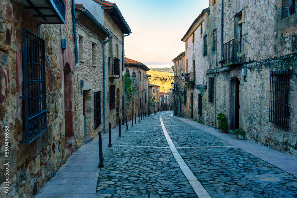 Picturesque alley with old houses and steep street at sunset in Siguenza, Spain