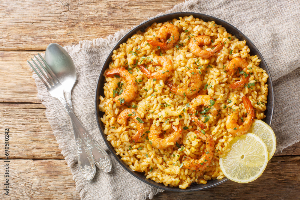 Shrimp risotto pairing the bold flavors of Parmesan and lemon with creamy rice and juicy shrimp closeup on the plate on the wooden table. Horizontal top view from above Shrimp risotto pairing the bold flavors of Parmesan and lemon with creamy rice and juicy shrimp closeup on the plate on the wooden table. Horizontal top view from above