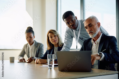 Group of business people using laptop during meeting in office.