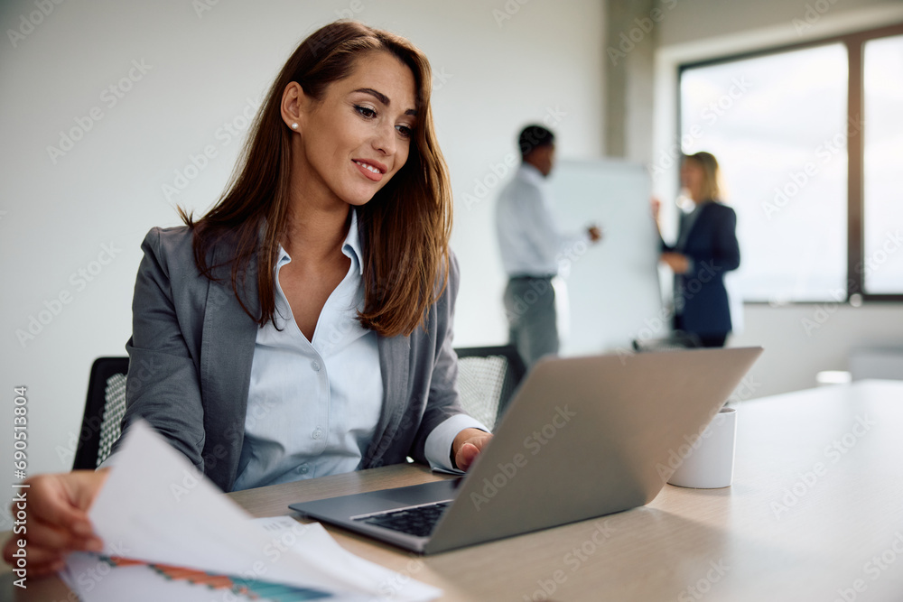 Happy businesswoman working on laptop in office. Happy businesswoman working on laptop in office.