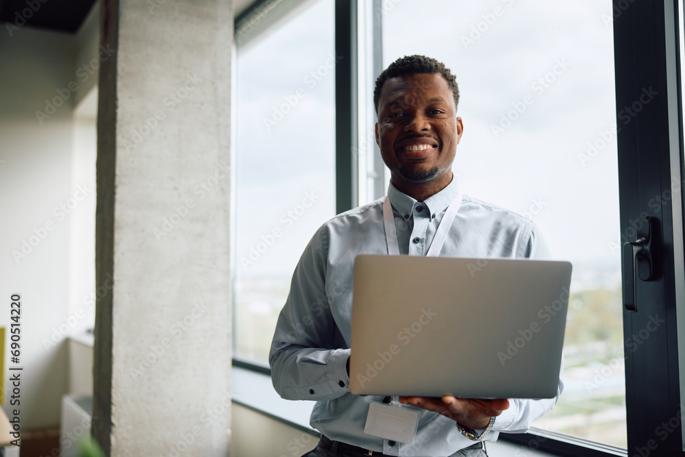 Happy black entrepreneur working on laptop at corporate office and looking at camera. Happy black entrepreneur working on laptop at corporate office and looking at camera.