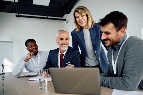 Happy business team using laptop during meeting in office.