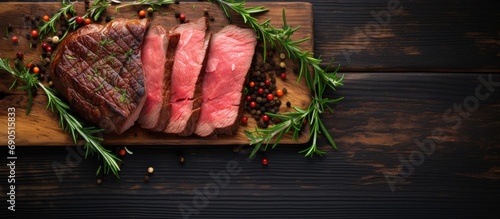 Dry aged sliced roast beef steak with herbs on an old cutting board, top view with copy space