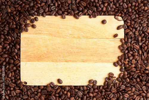 Top view of roasted coffee beans texture background on flat lay in horizontal with wooden board (cutting board) free space in center. pattern for design menu drink. coffee beans frame.