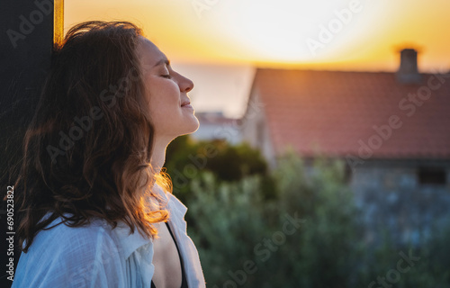 Fotografie Young cheerful woman enjoying a beautiful moment at sunset