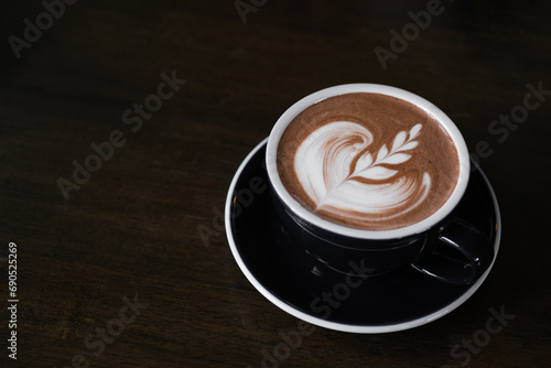 hot latte coffee or chocolate with latte art in the cup on the wooden table. Cafe drink and food menu concept. Copy space for text.
