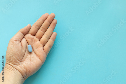 Фотография close up top view man hand with Prep pills on blue background with space for wor