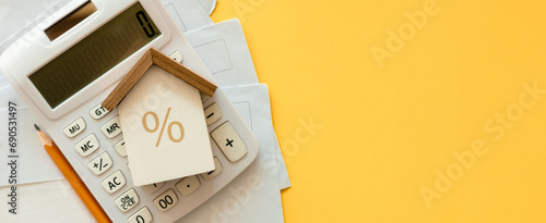 close up top view on home model with calculator and invoice mail on yellow color background with space for money management ,home loan and personal financial concept