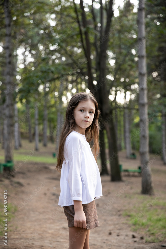 Portrait of a pretty little girl, looking at the camera, posing in the park. Portrait of a pretty little girl, looking at the camera, posing in the park.